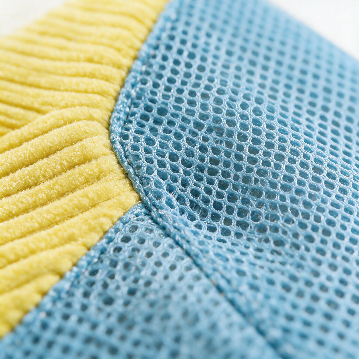 Macro du panneau d'aération en filet bleu cousu au tissu côtelé jaune du sac Talyss